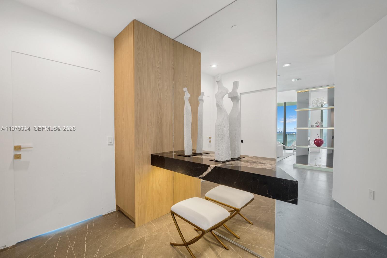 A modern entryway features a floating marble console, wooden cabinetry, and two white stools — 2900 NE 7th Ave # 4602, Miami FL 33137, MIAMI, FL