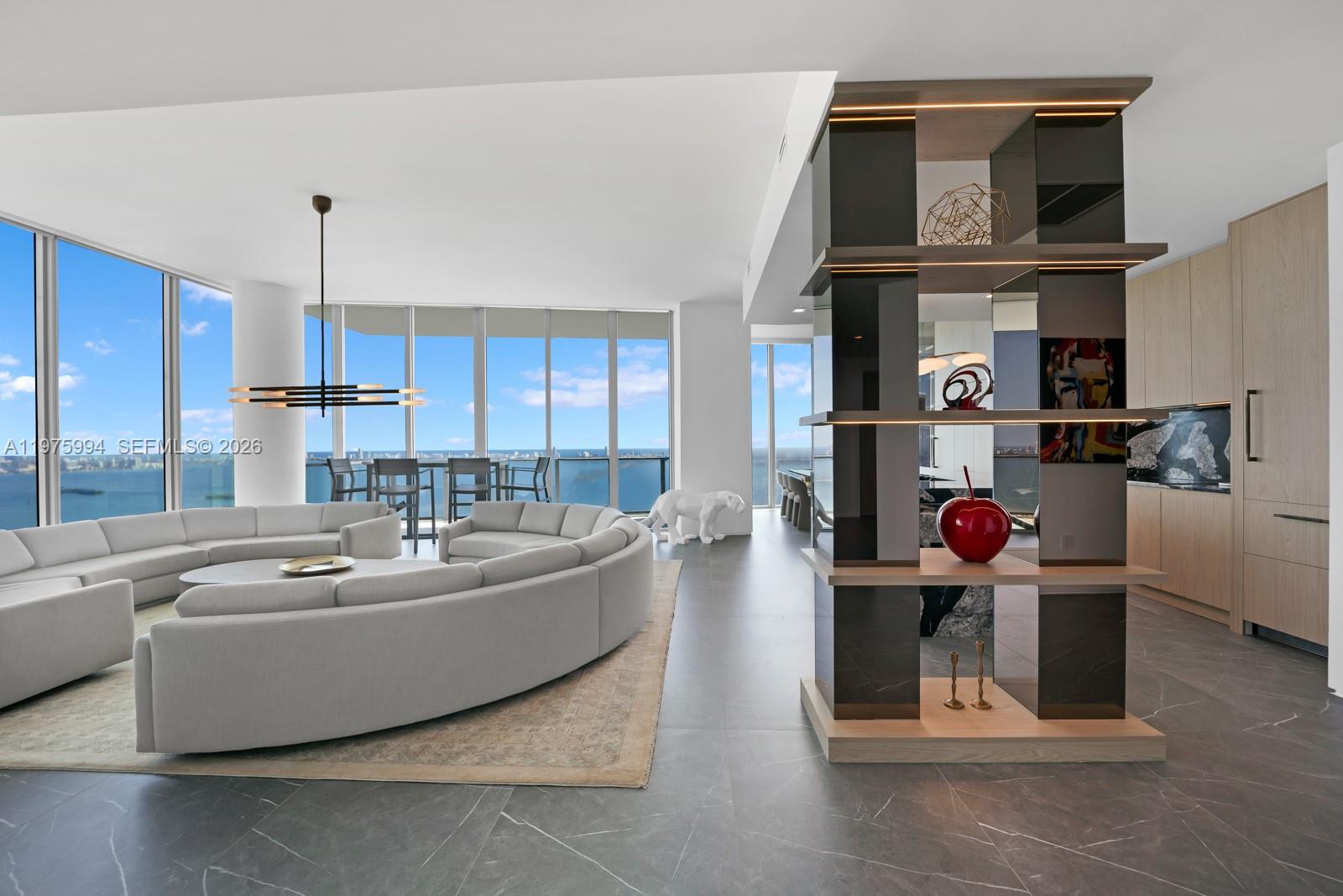 A modern living room features a curved sofa, a decorative shelving unit, and floor-to-ceiling windows — 2900 NE 7th Ave # 4602, Miami FL 33137, MIAMI, FL