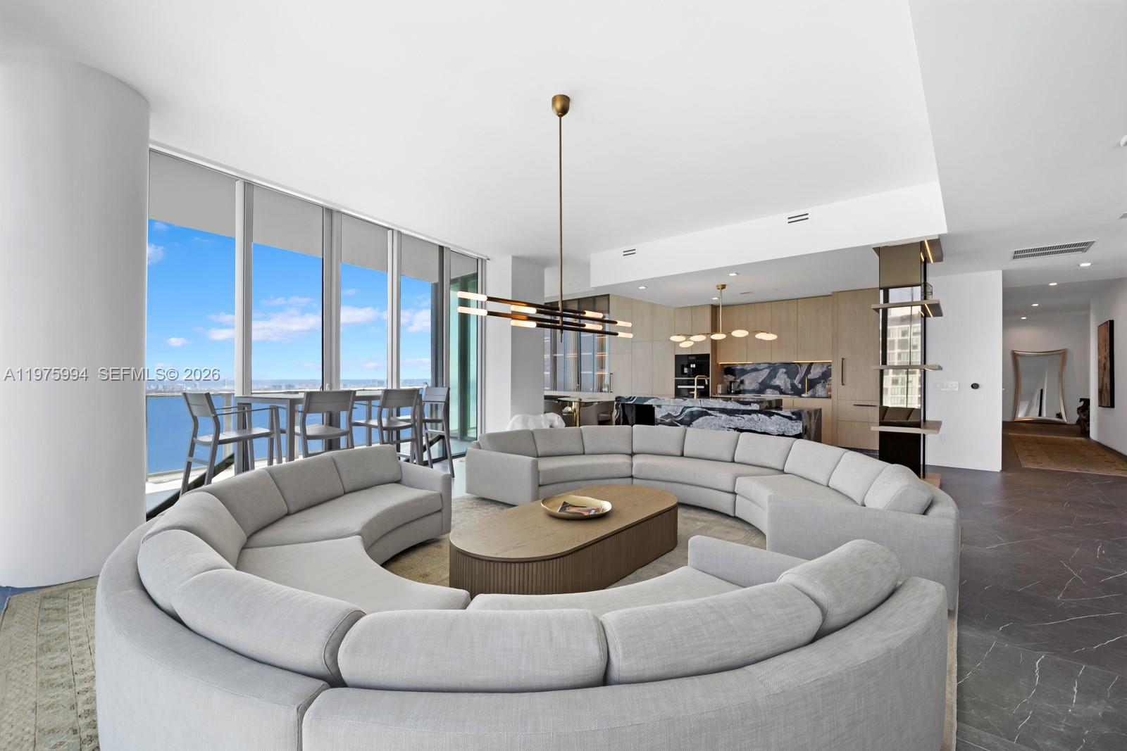 A modern living room features a large curved sofa, a coffee table, and floor-to-ceiling windows — 2900 NE 7th Ave # 4602, Miami FL 33137, MIAMI, FL