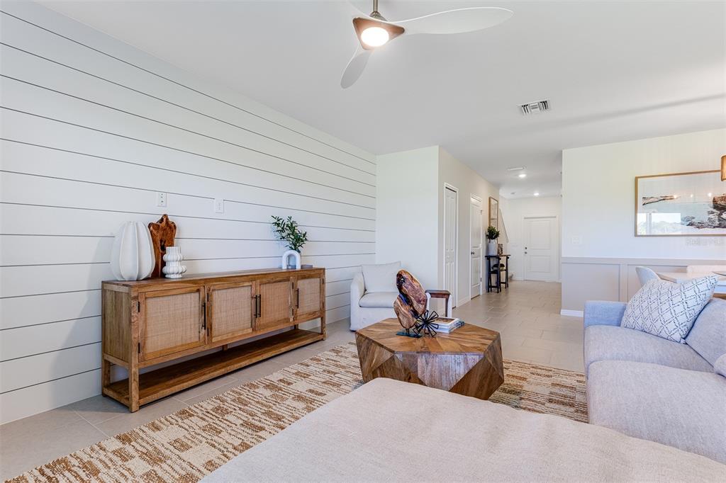 A living room features a shiplap wall, a wooden sideboard, and a geometric coffee table — 26593 JASPER WAY, PUNTA GORDA, FL