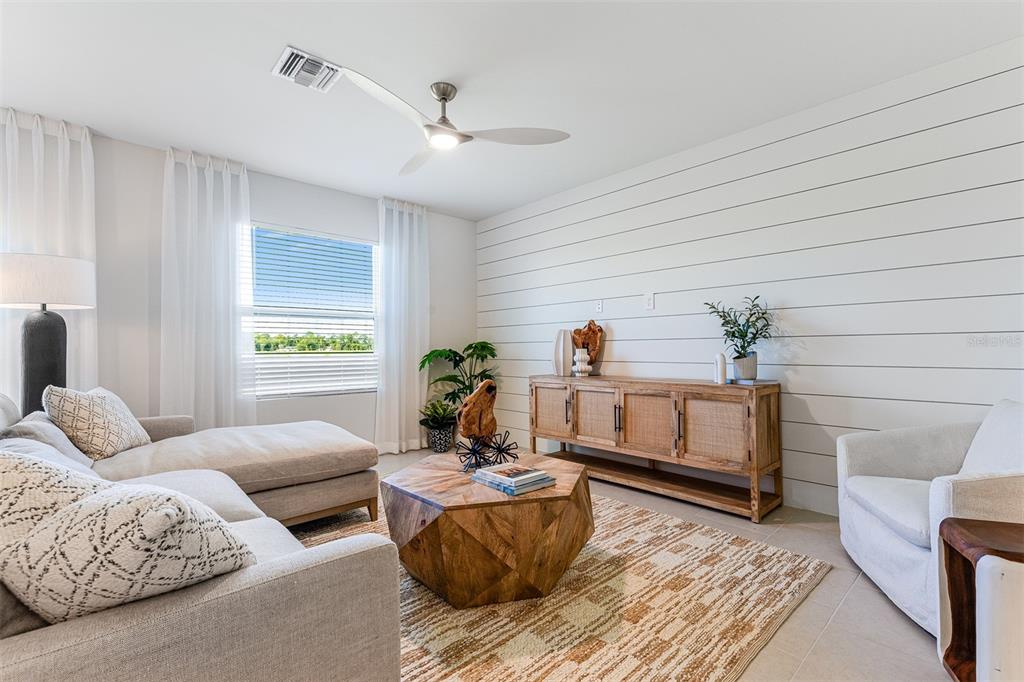 A living room features a shiplap accent wall, a wooden coffee table, and neutral furniture — 26593 JASPER WAY, PUNTA GORDA, FL