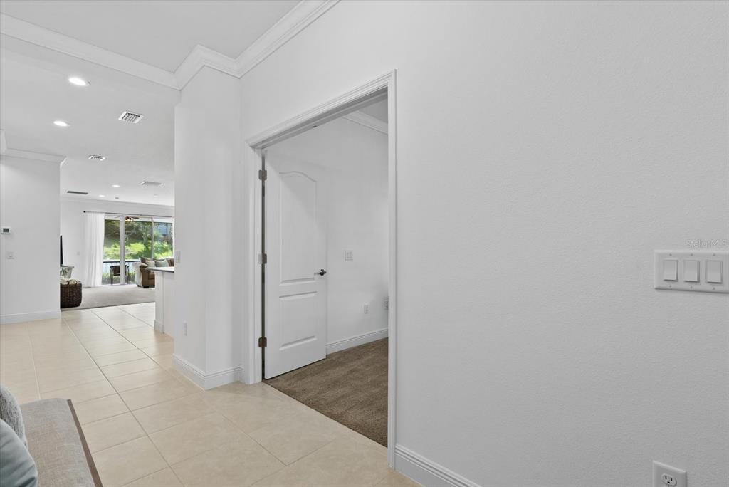 A hallway with tile flooring leads to a carpeted room through an open doorway — 7526 RIDGELAKE CIRCLE, BRADENTON, FL