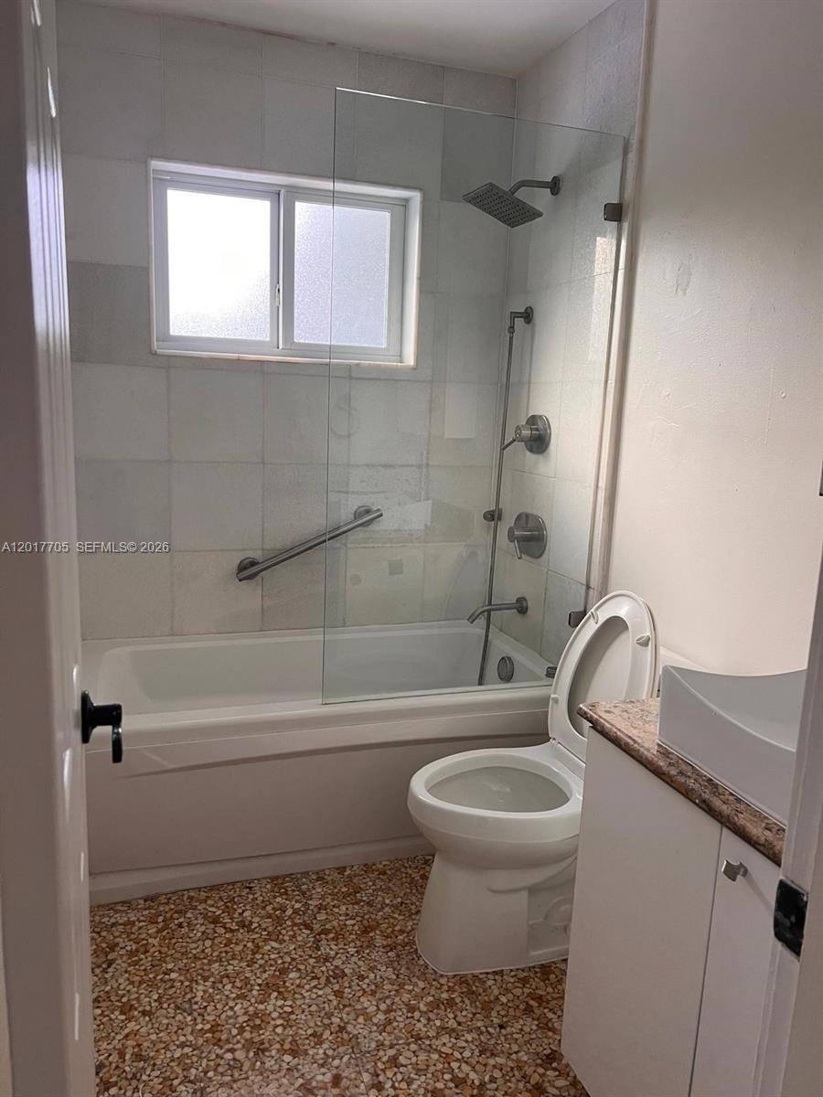 A bathroom features a bathtub with a glass shower screen, a toilet, and tiled flooring — 9770 SW 77th Ter, Miami FL 33173, MIAMI, FL