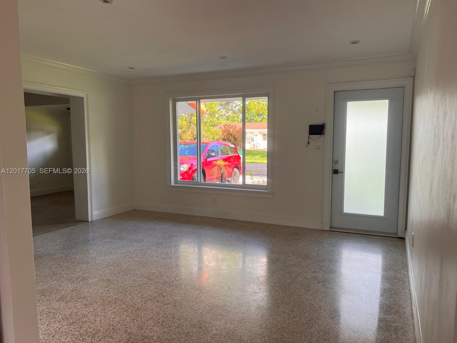 An empty room features white walls, recessed lighting, a large window, and polished terrazzo flooring — 9770 SW 77th Ter, Miami FL 33173, MIAMI, FL