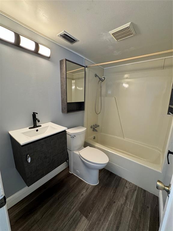 A bathroom features a vanity with a black faucet, a toilet, and a shower-tub combo — 700 E AIRPORT BOULEVARD UNIT G4, SANFORD, FL