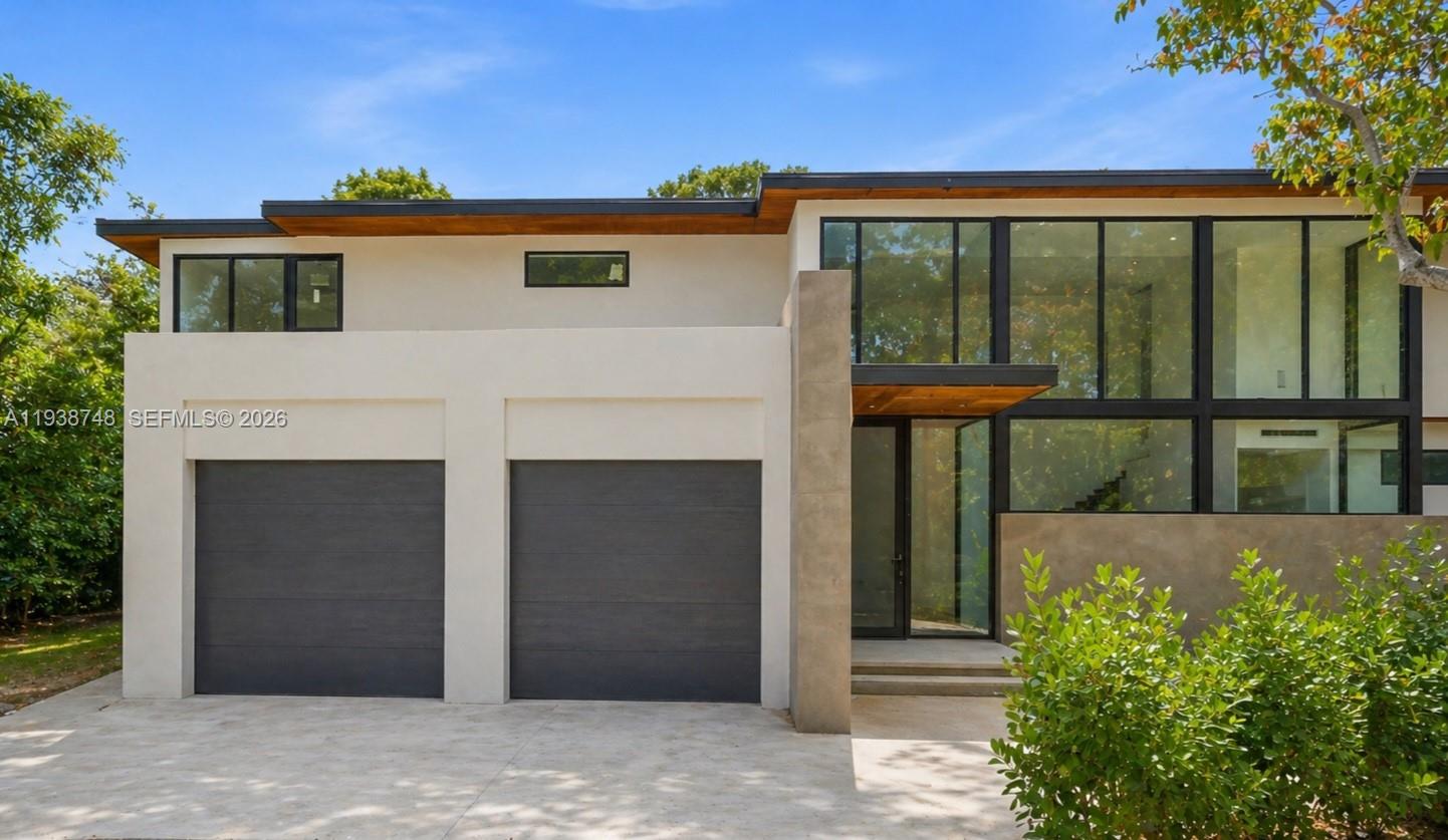 The exterior of a modern two-story house features a two-car garage and large glass windows — 4150 Loquat Ave, Miami FL 33133, MIAMI, FL