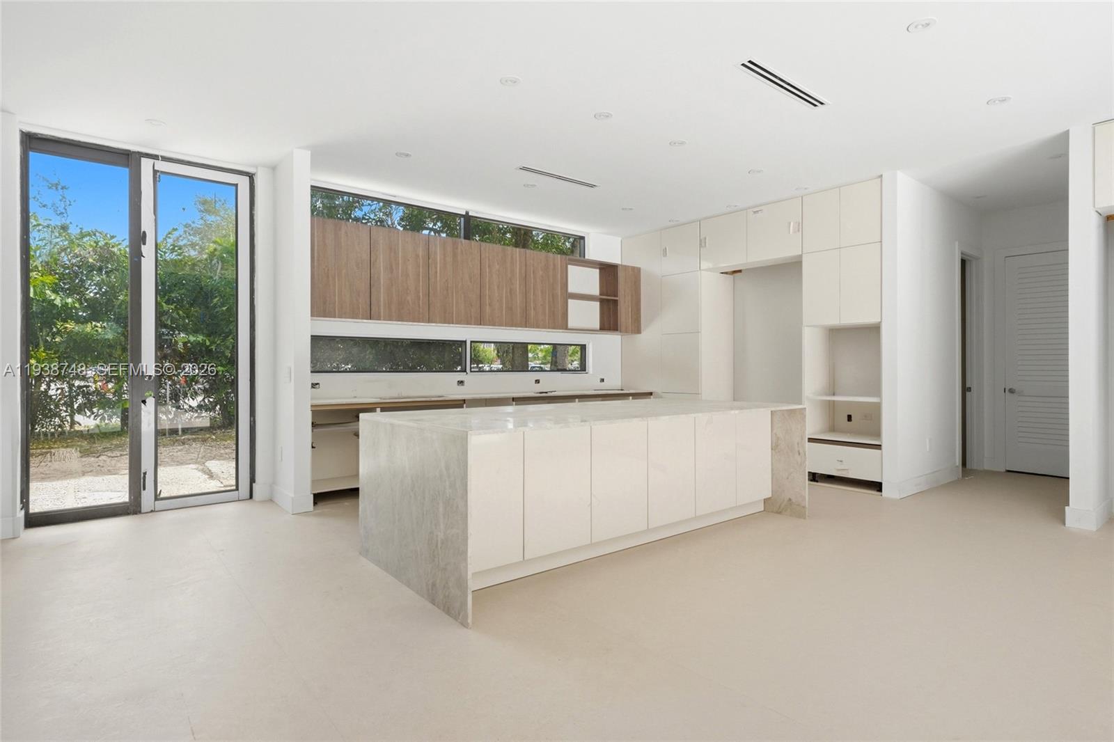 A modern kitchen features a large stone island, white cabinetry, and horizontal wood-toned upper cabinets — 4150 Loquat Ave, Miami FL 33133, MIAMI, FL