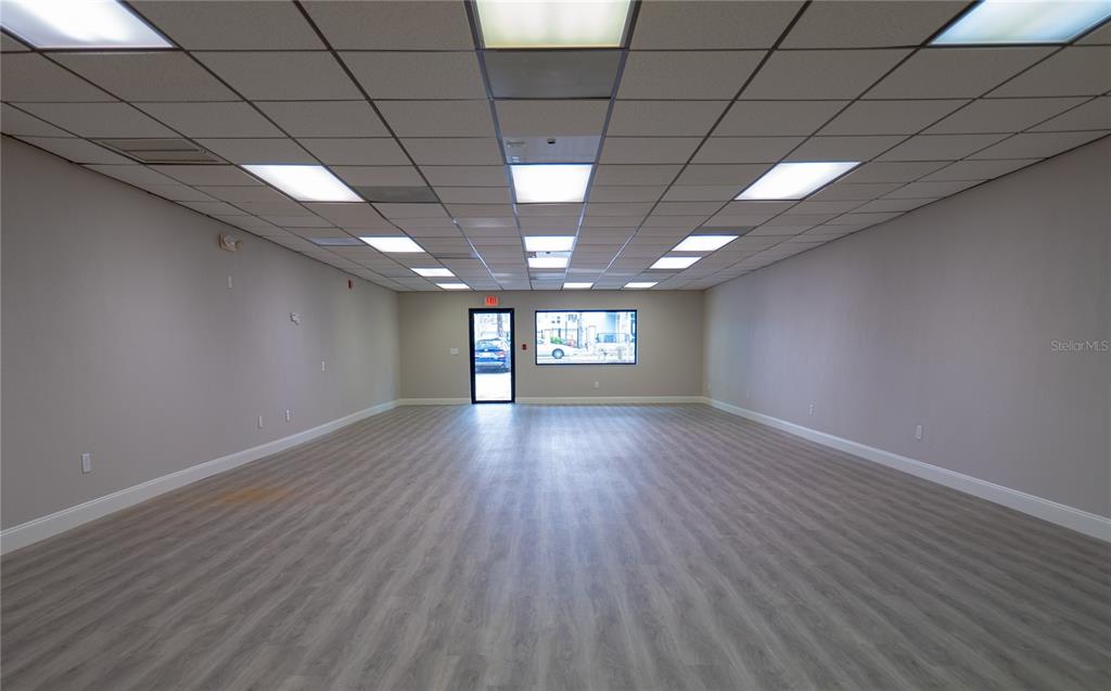 An empty commercial space features light wood-look flooring, gray walls, and a drop ceiling — 190 PATRICIA AVENUE UNIT 4, DUNEDIN, FL