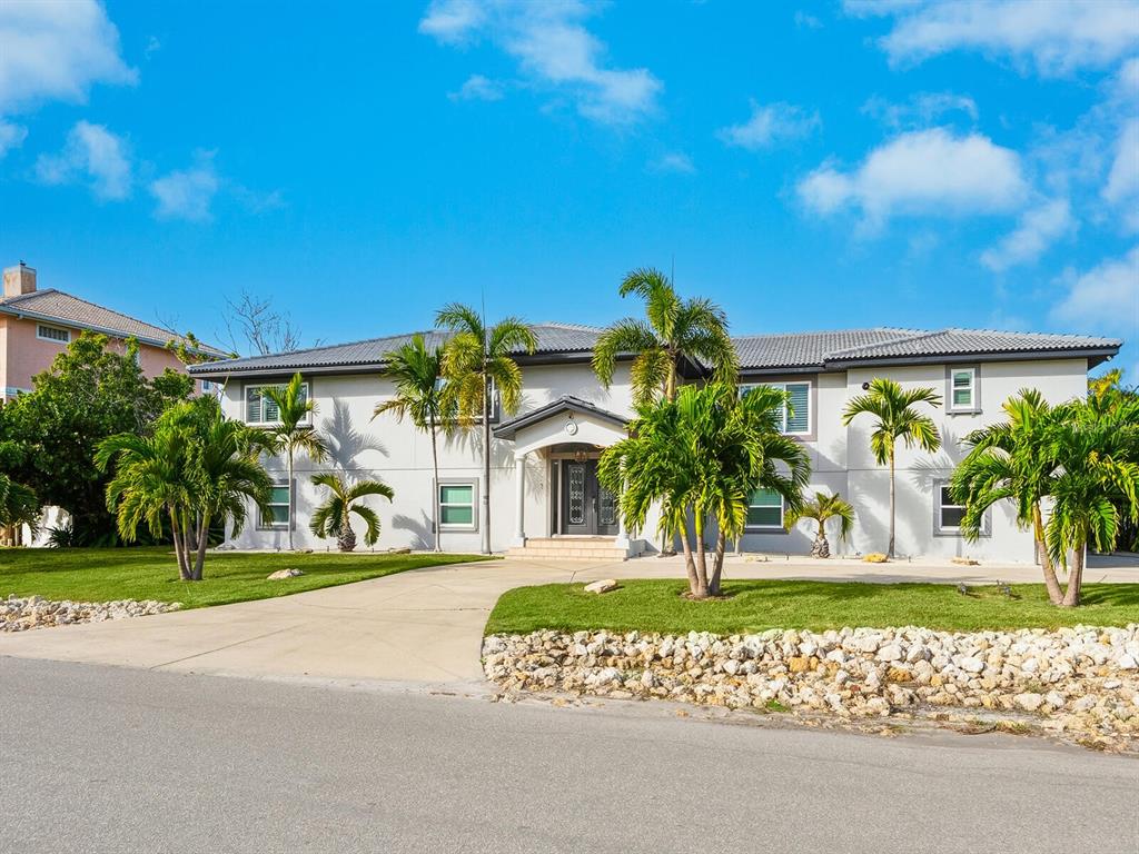 A two-story light-colored house with a tiled roof, palm trees, and a concrete driveway — 501 NORTON STREET, LONGBOAT KEY, FL