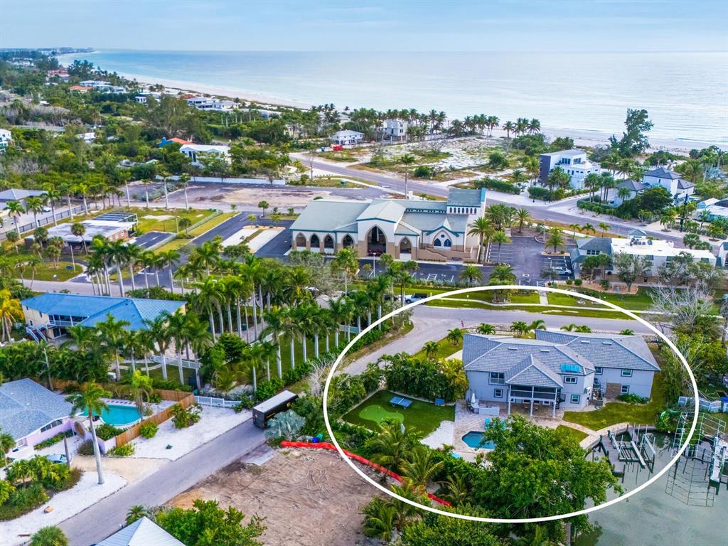 An aerial view shows a coastal house with a pool, putting green, and private dock — 501 NORTON STREET, LONGBOAT KEY, FL