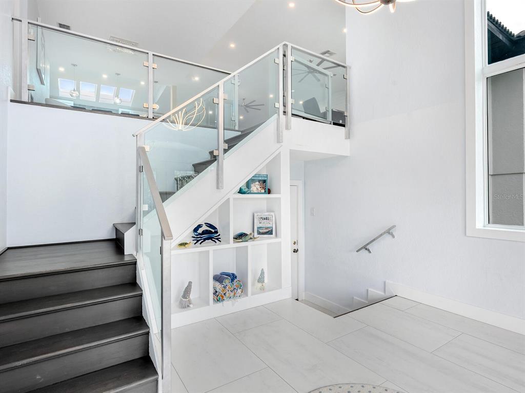 A staircase with glass railings and built-in shelving leads to an upper landing — 501 NORTON STREET, LONGBOAT KEY, FL