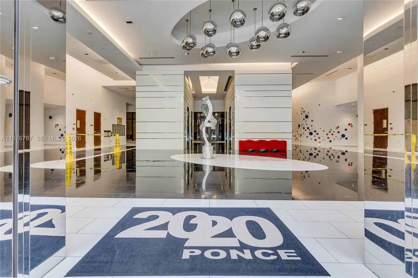 A modern building lobby features a white floor mat, reflective black tile, and spherical pendant lights — 2020 Ponce De Leon Blvd # A1, Coral Gables FL 33134, CORAL GABLES, FL