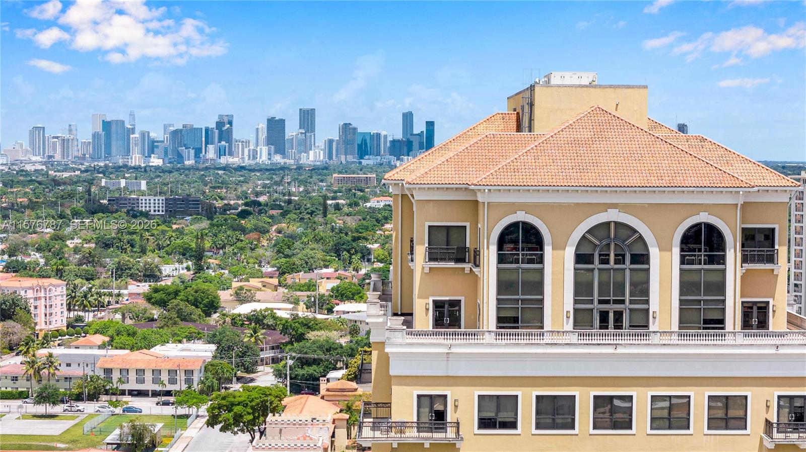 An exterior view of a multi-story building with a tiled roof overlooking a city skyline — 2020 Ponce De Leon Blvd # A1, Coral Gables FL 33134, CORAL GABLES, FL