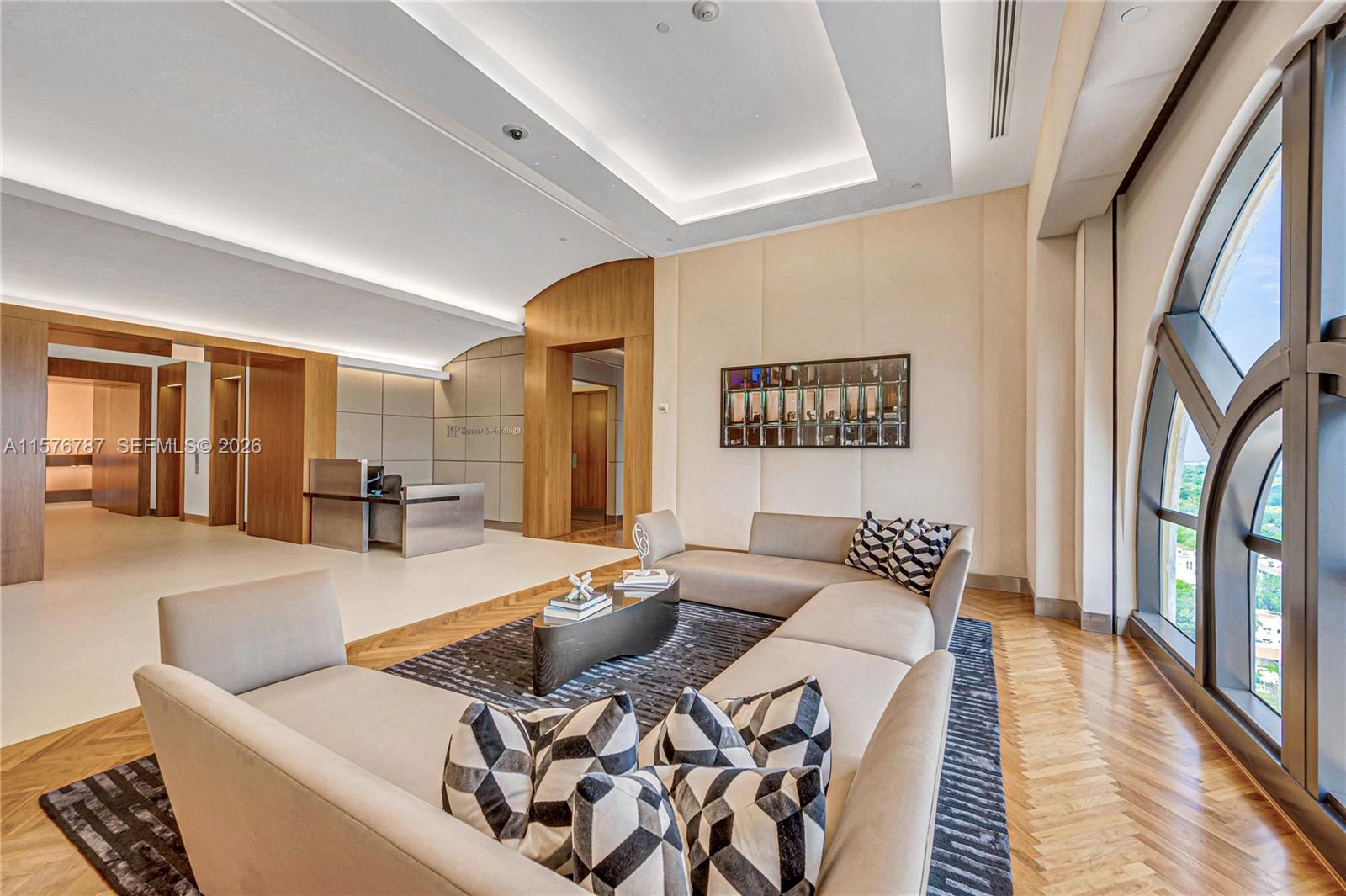 A modern office reception area features a curved sofa, wood flooring, and large arched windows — 2020 Ponce De Leon Blvd # A1, Coral Gables FL 33134, CORAL GABLES, FL