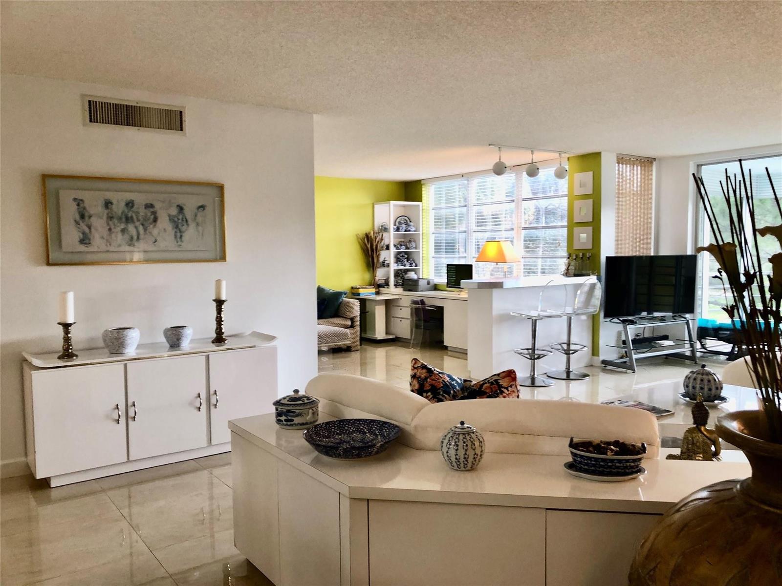 A bright living room features white cabinetry, a lime green accent wall, and tiled floors — 800 Cypress Grove Drive # 204, Pompano Beach FL 33069, POMPANO BEACH, FL