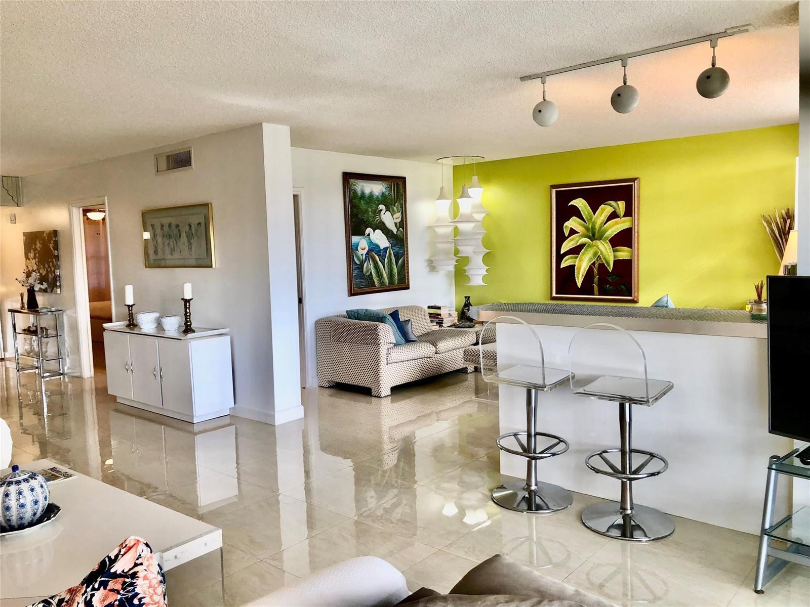 A living room features a lime green accent wall, tiled floors, and a breakfast bar — 800 Cypress Grove Drive # 204, Pompano Beach FL 33069, POMPANO BEACH, FL