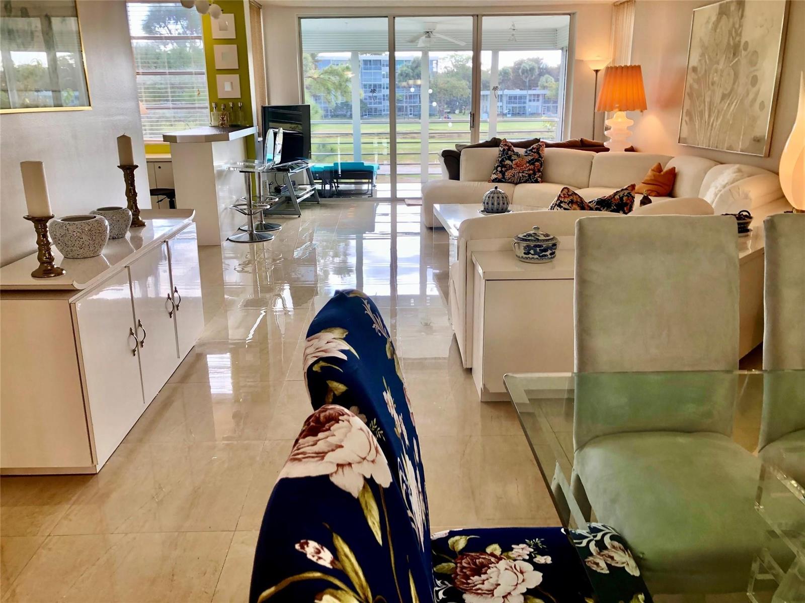 A bright living and dining area features glossy tile floors, white furniture, and large windows — 800 Cypress Grove Drive # 204, Pompano Beach FL 33069, POMPANO BEACH, FL