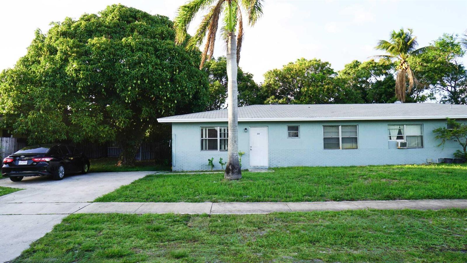 A light blue, single-story house with a palm tree in the front yard — 233 SE 26th Avenue, Boynton Beach FL 33435, BOYNTON BEACH, FL