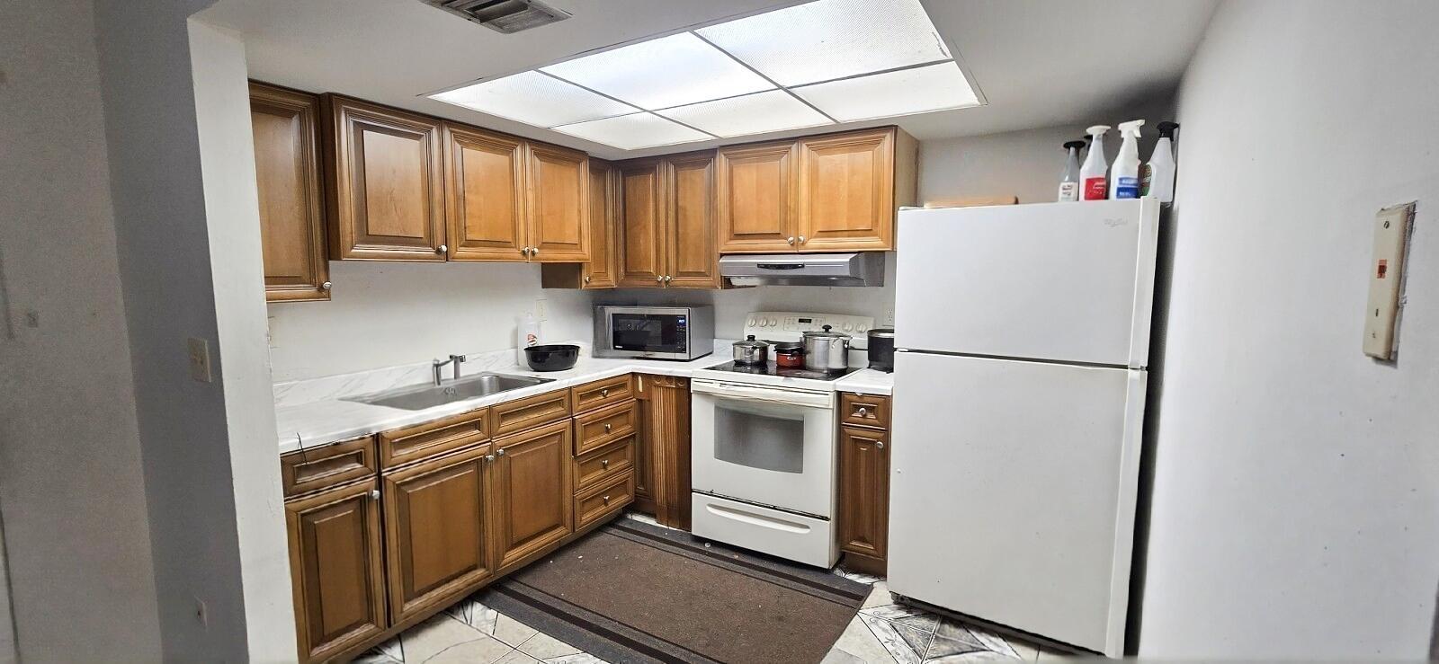 A kitchen features wood cabinets, white appliances, a drop-in sink, and a drop ceiling — 233 SE 26th Avenue, Boynton Beach FL 33435, BOYNTON BEACH, FL