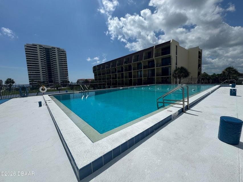An outdoor swimming pool is situated in front of a multi-story hotel building — 1441 N ATLANTIC AVENUE UNIT 216, DAYTONA BEACH, FL