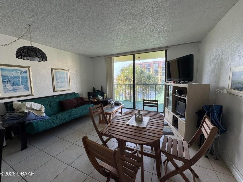 A living and dining area features a green sofa, wooden table, and balcony access — 1441 N ATLANTIC AVENUE UNIT 216, DAYTONA BEACH, FL