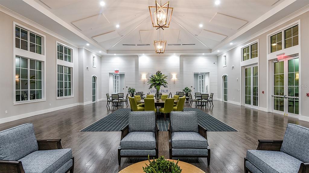 A spacious community room features dark wood floors, blue armchairs, and a central dining area — 21201 WACISSA DRIVE, VENICE, FL