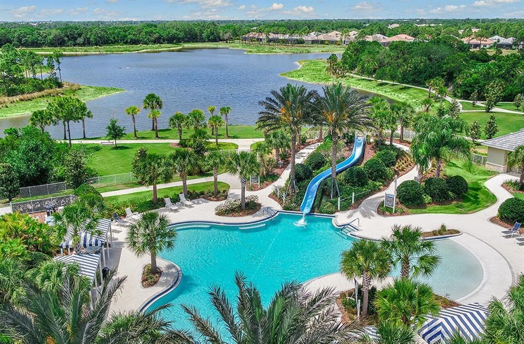 An aerial view of a swimming pool with a blue slide, palm trees, and lake — 21201 WACISSA DRIVE, VENICE, FL