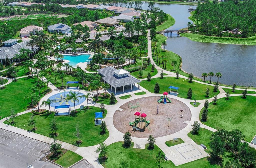 An aerial view shows a community park with a playground, swimming pool, and lake — 21201 WACISSA DRIVE, VENICE, FL