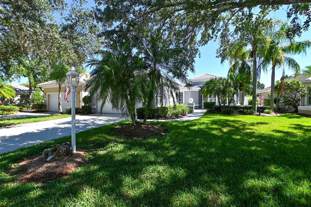 A single-story house with a driveway, palm trees, and a manicured lawn under a sunny sky — 7131 KENSINGTON COURT, UNIVERSITY PARK, FL