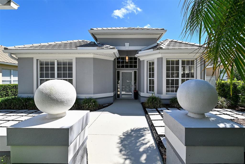 A gray single-story house features a central entryway with two large white spheres on pillars — 7131 KENSINGTON COURT, UNIVERSITY PARK, FL