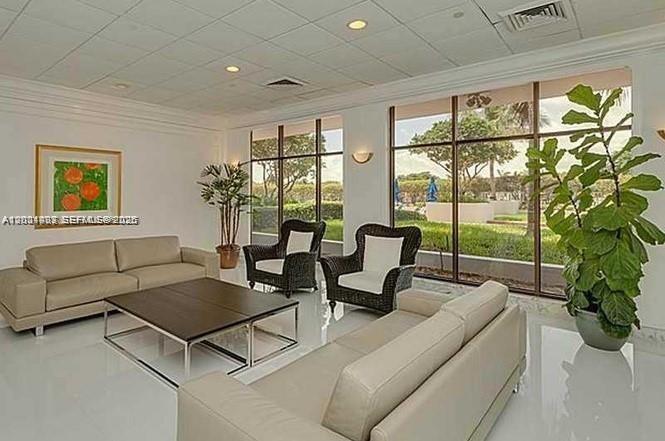 A bright, modern lounge features two beige sofas, two wicker armchairs, and large floor-to-ceiling windows — 5700 Collins Ave # 4N, Miami Beach FL 33140, MIAMI BEACH, FL
