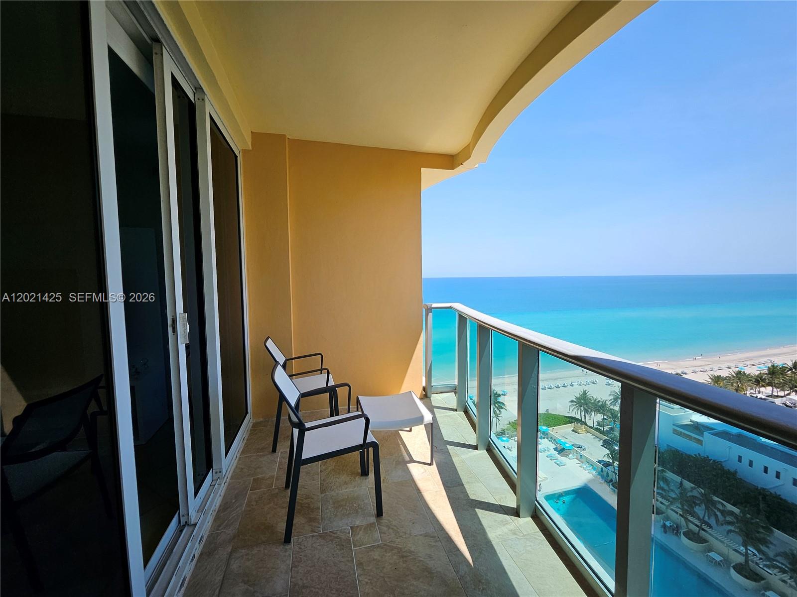 A balcony with tiled flooring and two chairs overlooks the ocean and a swimming pool — 2501 S Ocean Dr, Hollywood FL 33019, HOLLYWOOD, FL