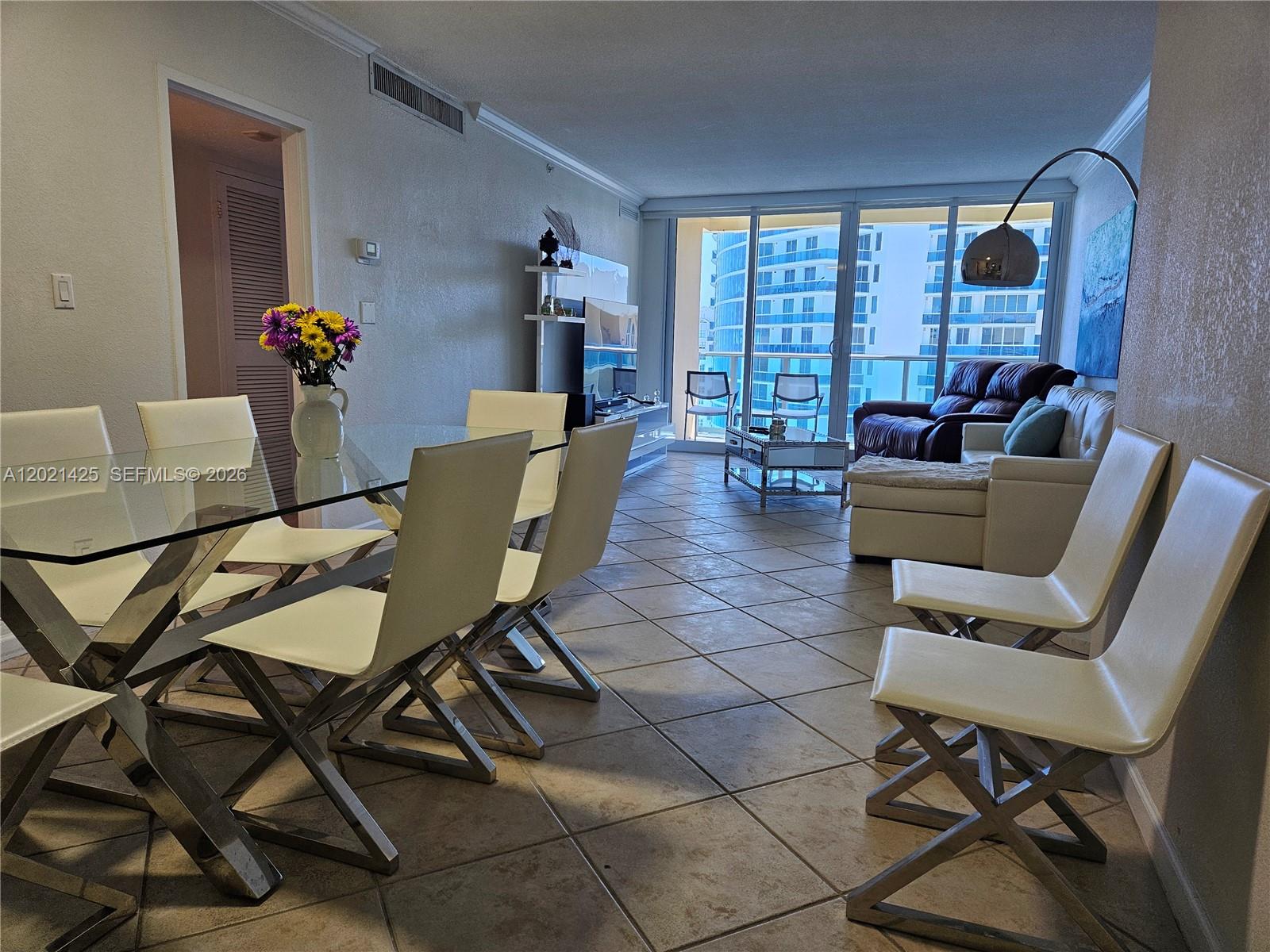 A dining area and living room feature tile floors, modern white furniture, and balcony views — 2501 S Ocean Dr, Hollywood FL 33019, HOLLYWOOD, FL