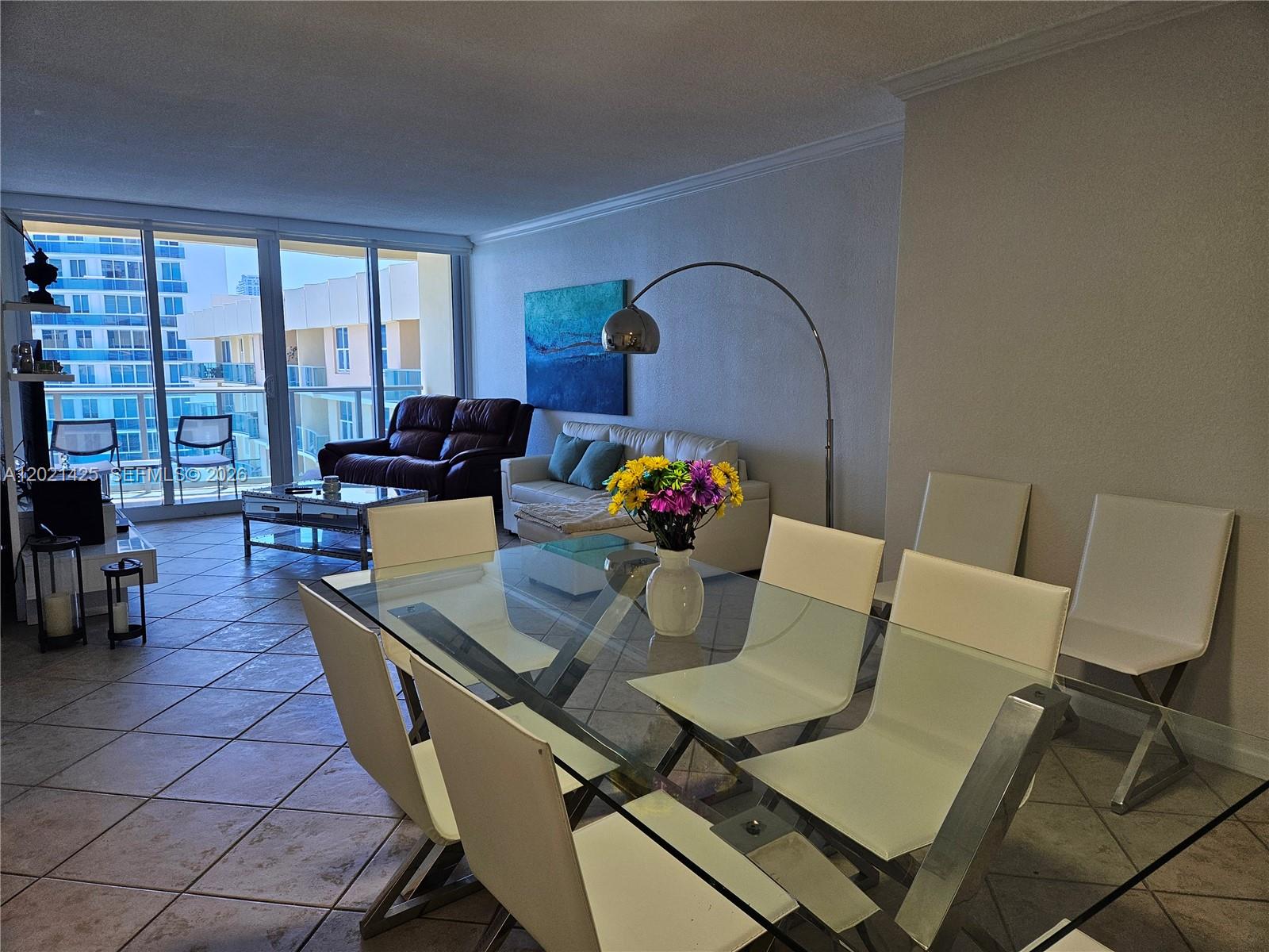 A dining area with a glass table and white chairs opens into a living room — 2501 S Ocean Dr, Hollywood FL 33019, HOLLYWOOD, FL