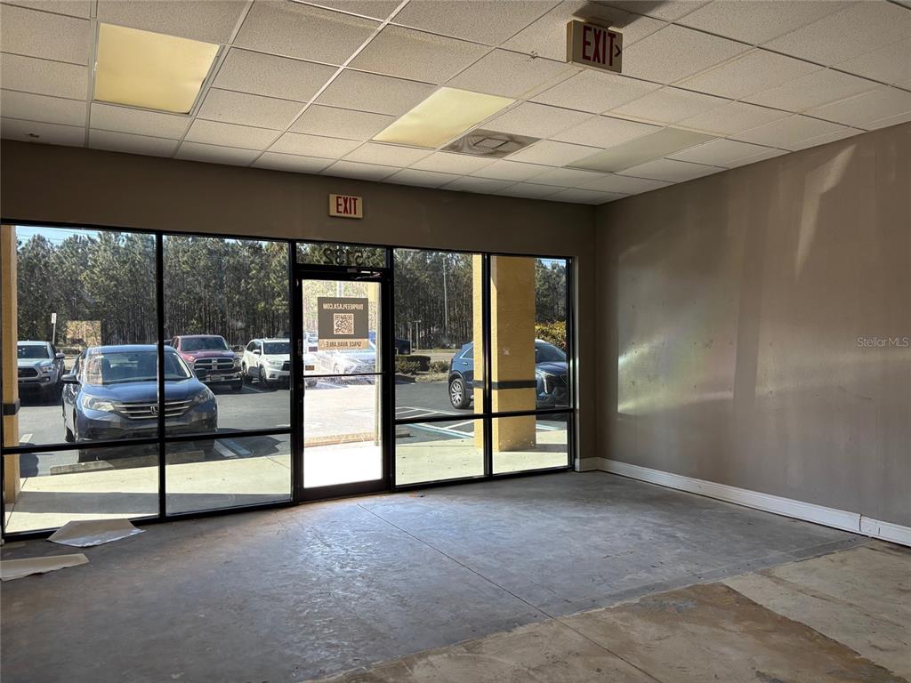 An empty commercial space features large glass windows, a glass door, and a drop ceiling — 5132 LAND O LAKES BOULEVARD UNIT 105, LAND O LAKES, FL