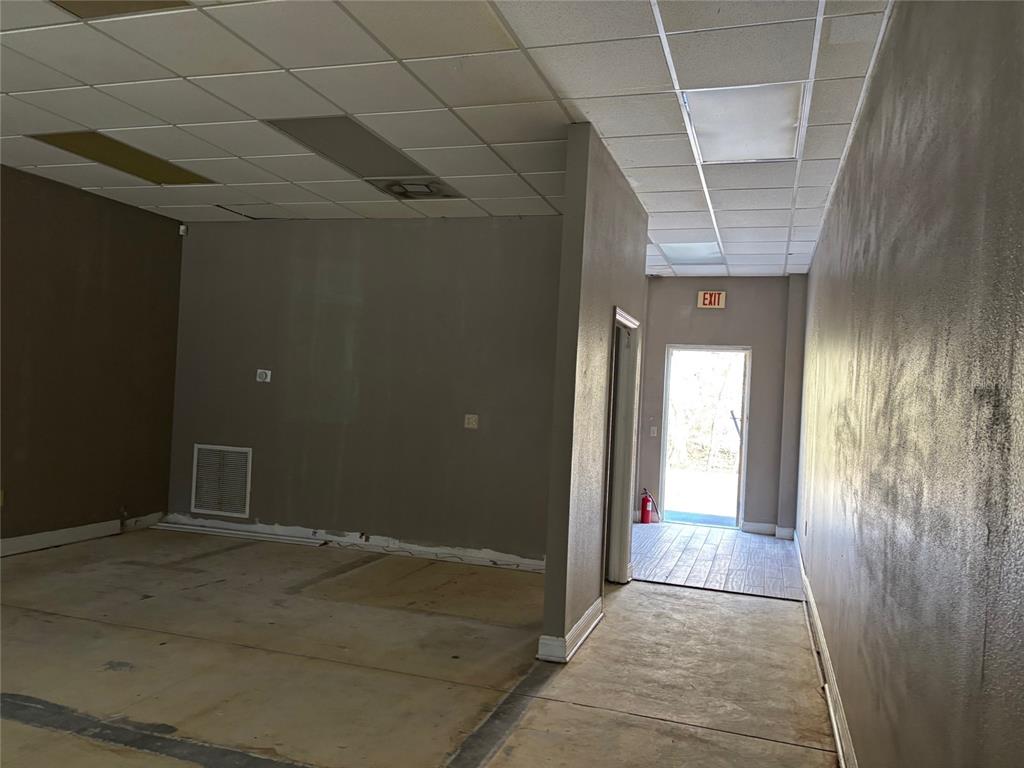 An empty commercial space with gray walls, a drop ceiling, and an exit door — 5132 LAND O LAKES BOULEVARD UNIT 105, LAND O LAKES, FL