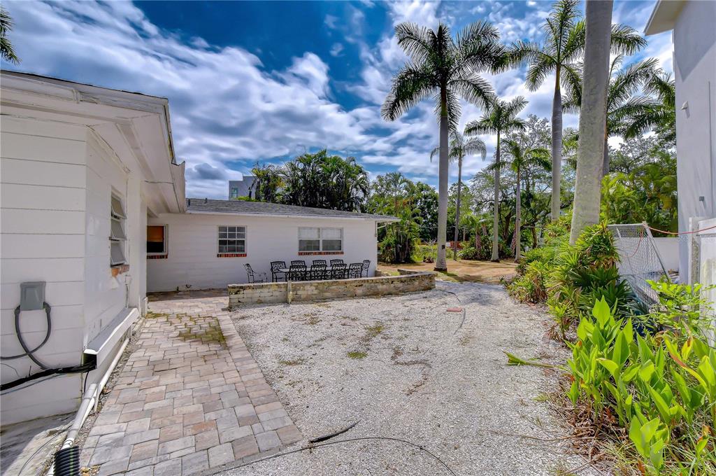 A backyard features a paved patio, a gravel area, and several tall palm trees — 5006 W DICKENS AVENUE, TAMPA, FL