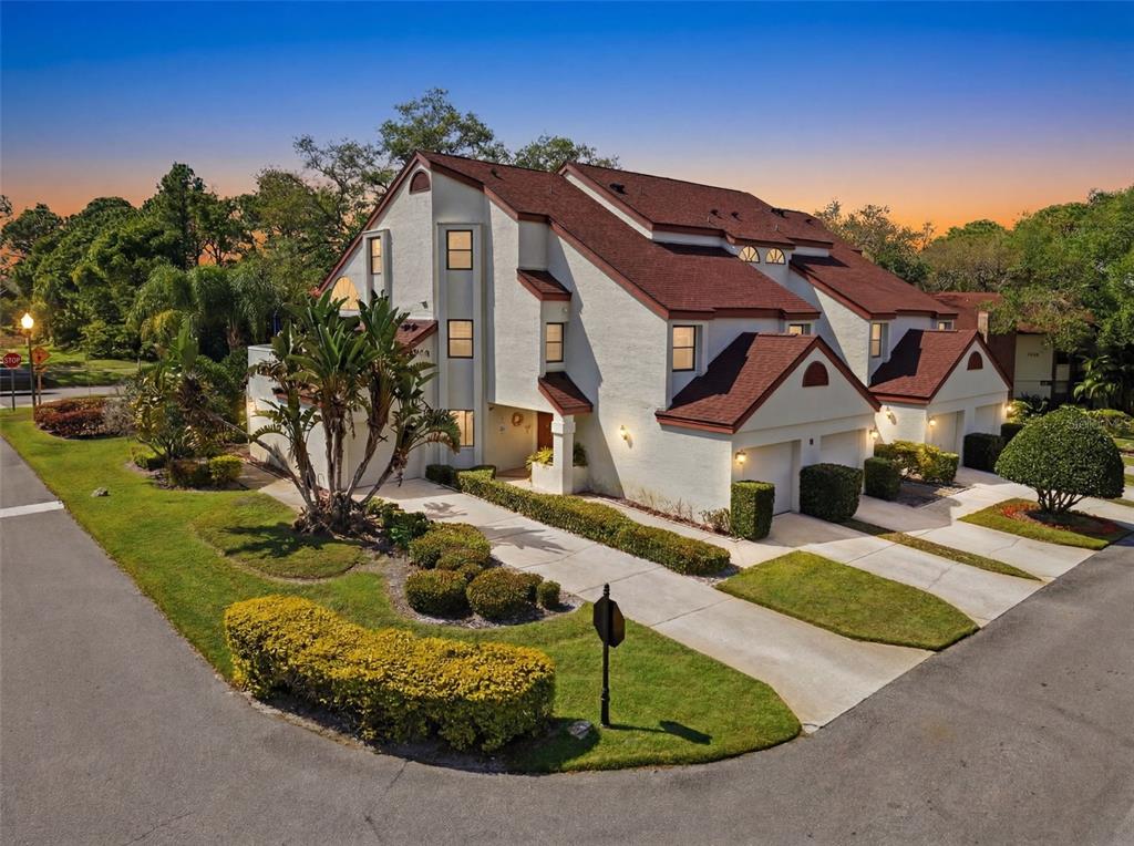An exterior view of a multi-unit townhouse complex with red roofs and beige stucco walls — 3455 COUNTRYSIDE BOULEVARD UNIT 98, CLEARWATER, FL