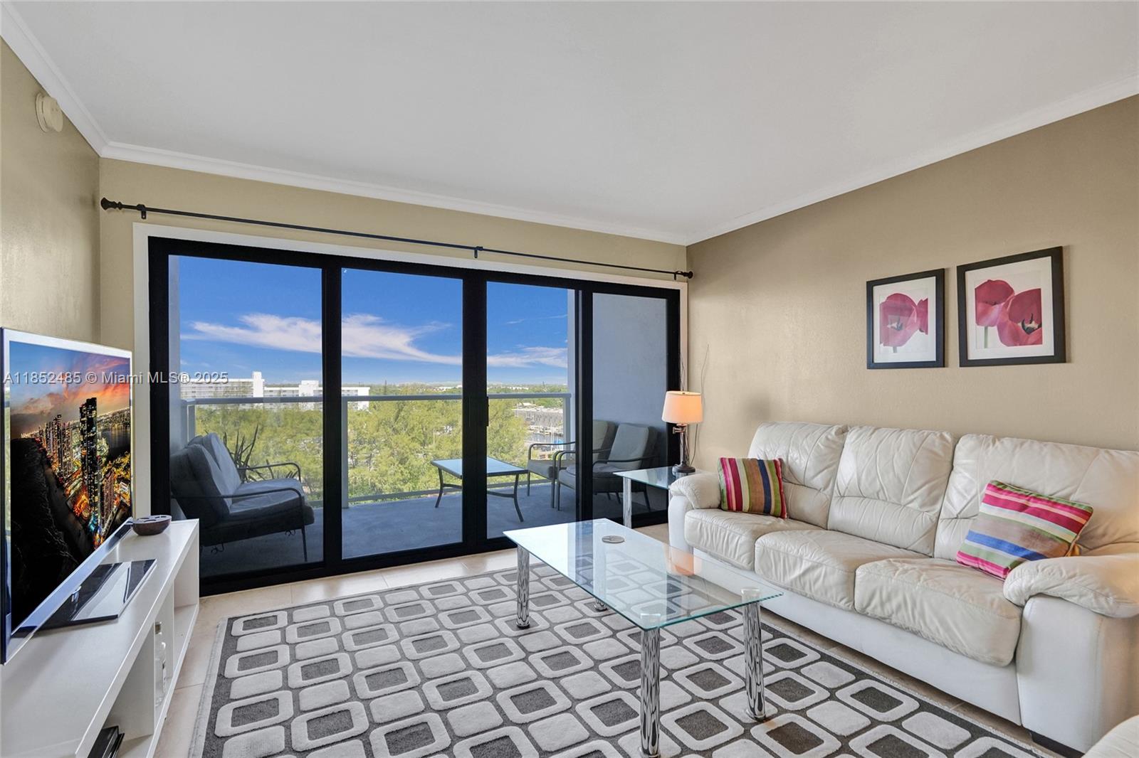 A living room features a white leather sofa, glass coffee table, and sliding doors to a balcony — 1401 N Riverside Dr # 1005, Pompano Beach FL 33062, POMPANO BEACH, FL