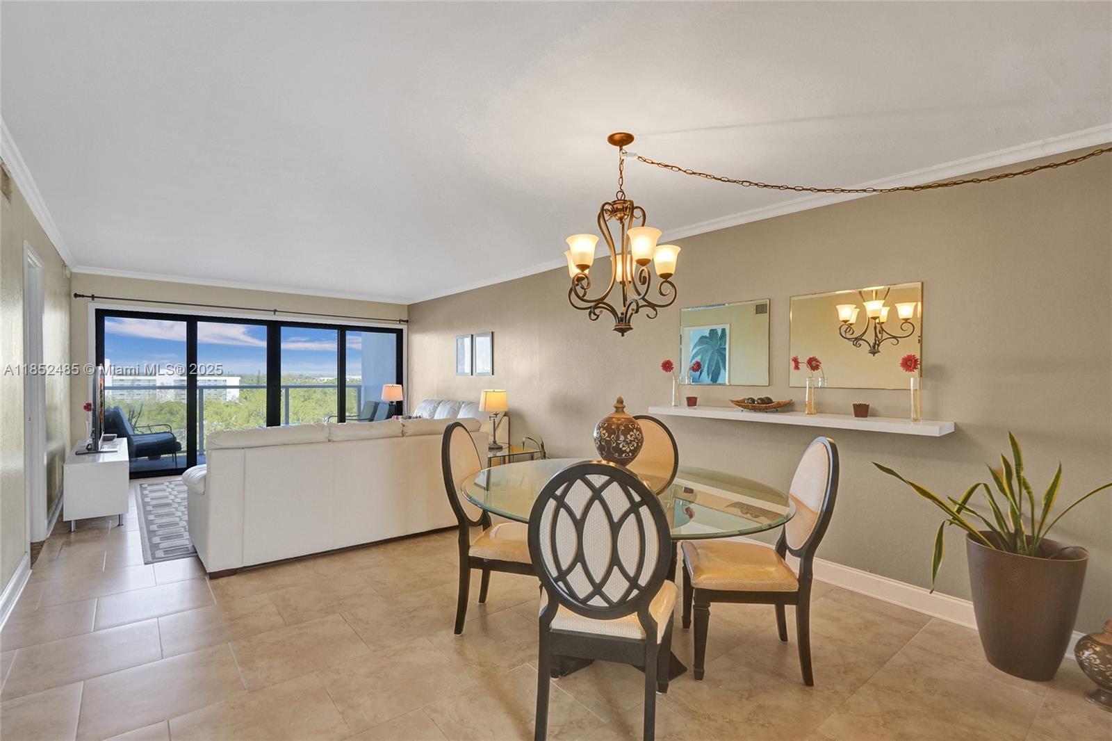 A dining area with a glass table and chandelier opens to a living room with balcony — 1401 N Riverside Dr # 1005, Pompano Beach FL 33062, POMPANO BEACH, FL