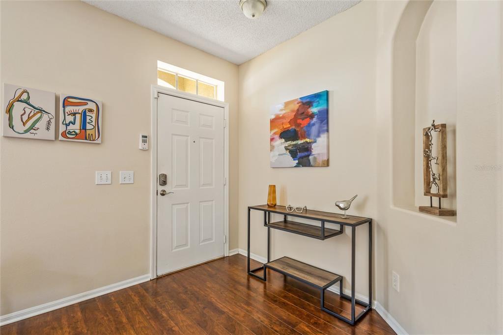 An entryway features dark wood flooring, a white front door, and a modern console table — 422 GRAYSTONE BOULEVARD, DAVENPORT, FL