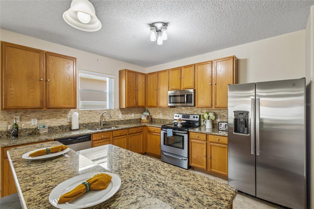 A kitchen with wood cabinets, granite countertops, and stainless steel appliances — 422 GRAYSTONE BOULEVARD, DAVENPORT, FL