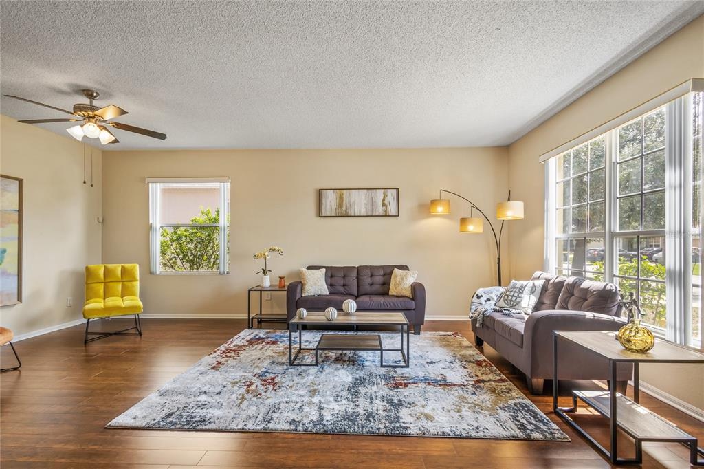 A living room features wood floors, a patterned area rug, two sofas, and a yellow chair — 422 GRAYSTONE BOULEVARD, DAVENPORT, FL