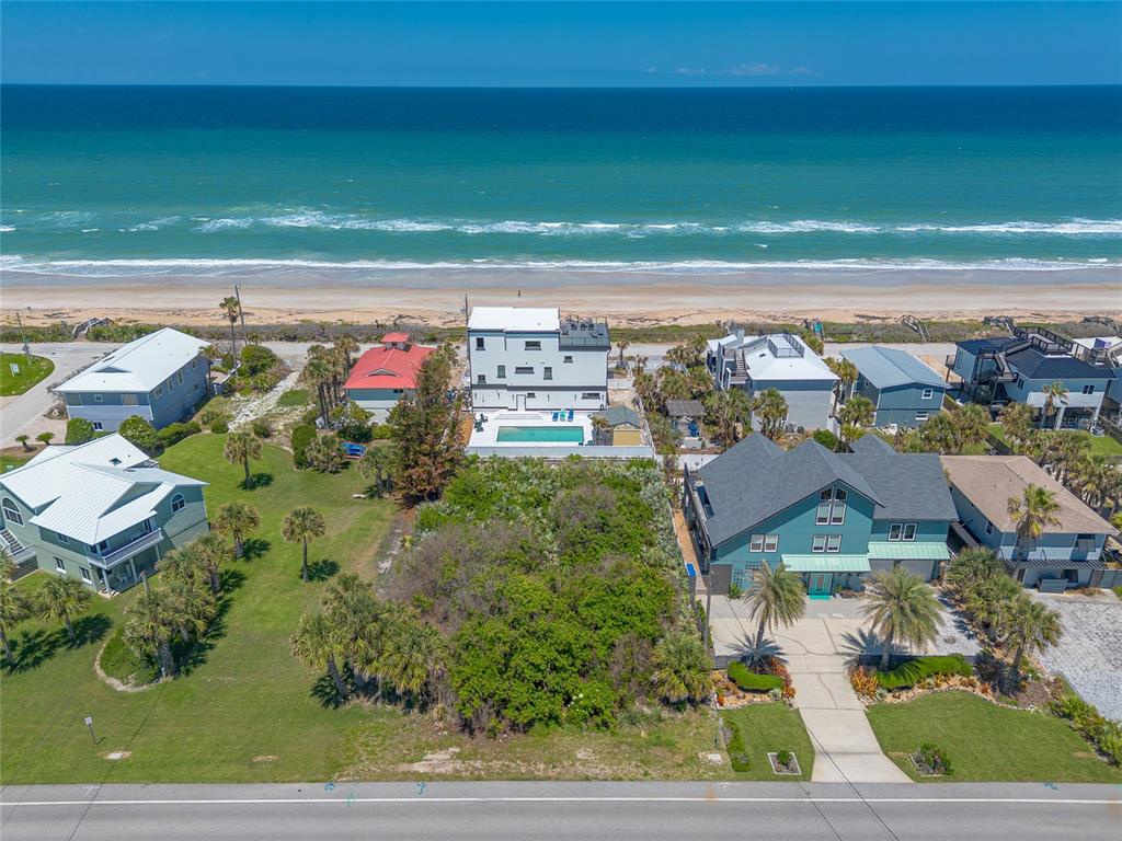 An aerial view shows a coastal property with a vacant lot between two houses — 6411 TURTLEMOUND ROAD, NEW SMYRNA BEACH, FL
