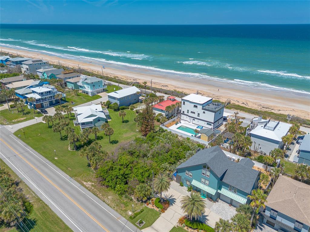 An aerial view shows several beach houses along a coastline next to a paved road — 6411 TURTLEMOUND ROAD, NEW SMYRNA BEACH, FL