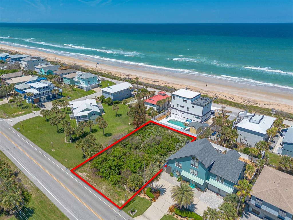 An aerial view shows a vacant, rectangular lot outlined in red next to a coastal house — 6411 TURTLEMOUND ROAD, NEW SMYRNA BEACH, FL