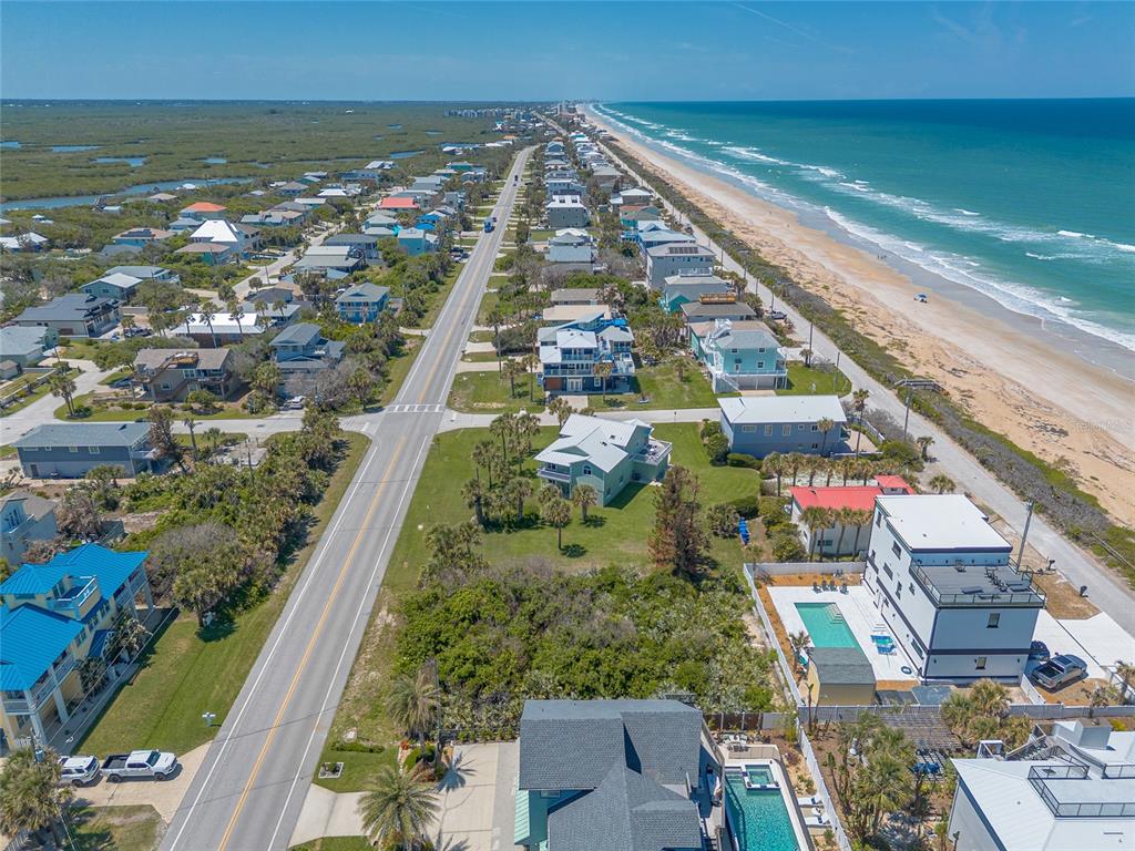 An aerial view shows a coastal road running parallel to a beach and residential homes — 6411 TURTLEMOUND ROAD, NEW SMYRNA BEACH, FL