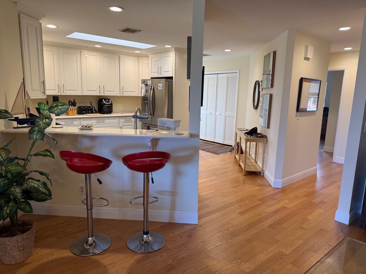 A kitchen with white cabinets and a breakfast bar featuring two red stools — 6102 SE Landing Way # 13, Stuart FL 34997, STUART, FL