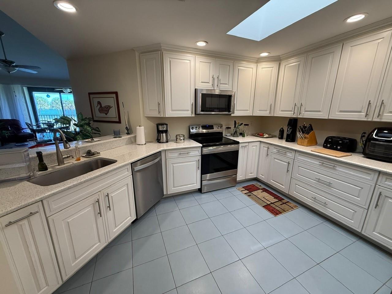 A kitchen with white cabinets, stainless steel appliances, light countertops, and blue tile flooring — 6102 SE Landing Way # 13, Stuart FL 34997, STUART, FL