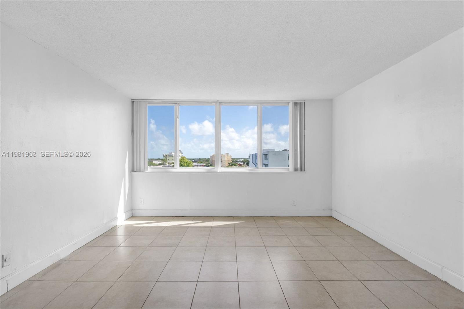 An empty room features white walls, light-colored tile flooring, and a large window with blinds — 9143 SW 77th Ave # B710, Miami FL 33156, MIAMI, FL